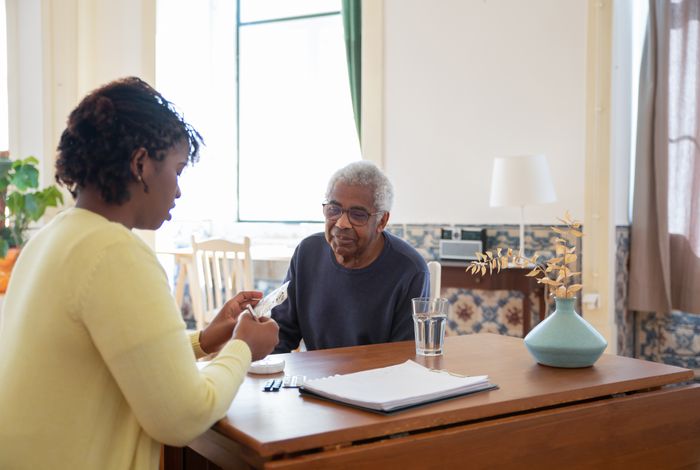 A caregiver assisting an elderly man with his medication